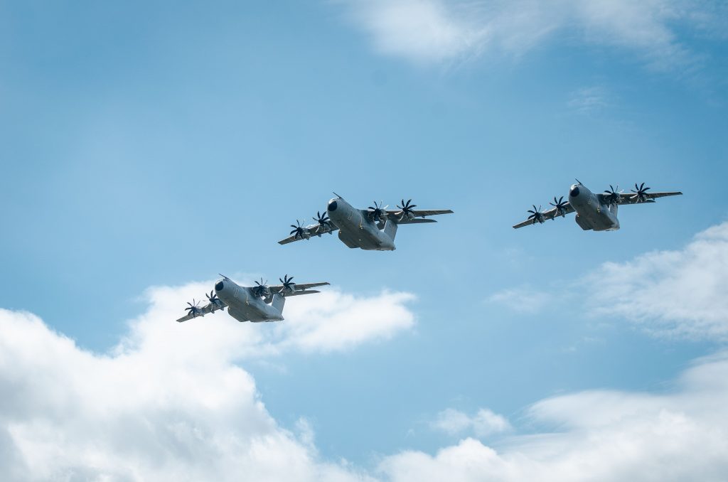 Three military aircraft flying in formation against a blue sky with clouds, showcasing power and precision.