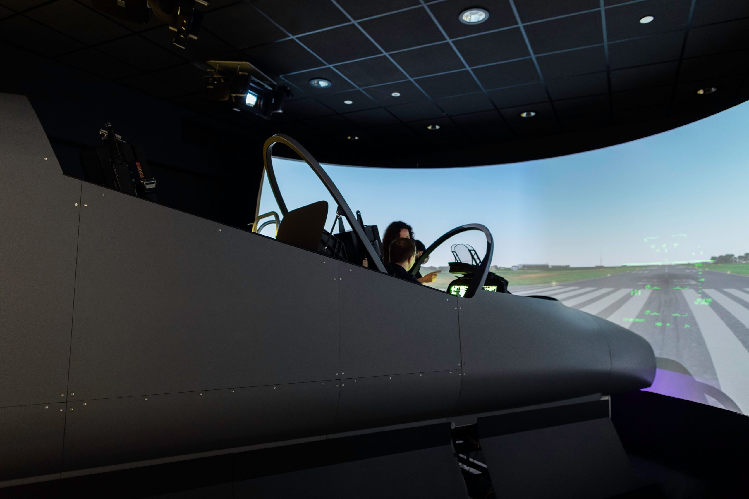 A female pilot operates a flight simulator in an advanced training facility.